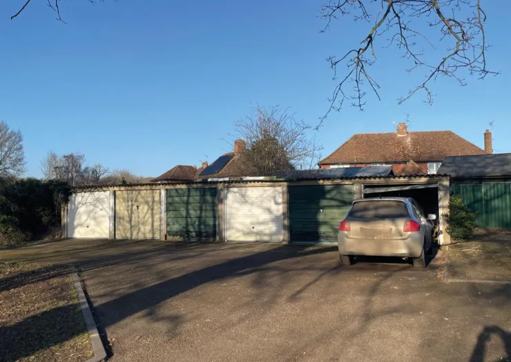 Row of colorful garages with a car backed into one, under a clear blue sky.