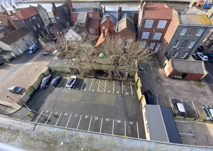 Aerial view of a numbered parking lot, surrounded by buildings and trees.
