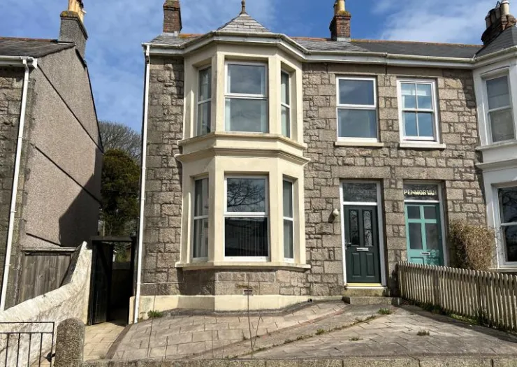 Stone terraced house with bay window, "Penmorva" on facade, and paved front drive.