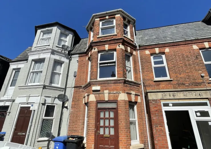 Red brick terraced house with bay window and "Victoria" inscribed above the entrance.