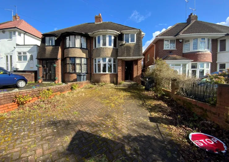 Brick semi-detached house with bay windows and overgrown front driveway. A discarded "STOP" sign lies on the ground.