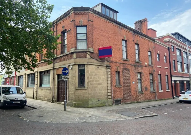 Red brick corner building with "One Way" street sign.