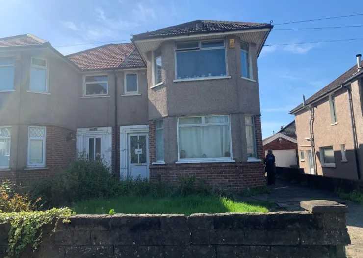 Semi-detached house with bay windows and front garden, seen on a sunny day.