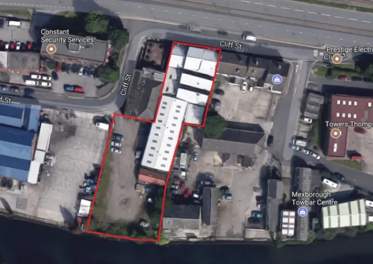 Aerial view of commercial property on Cliff St, outlined in red, with surrounding businesses and a river.