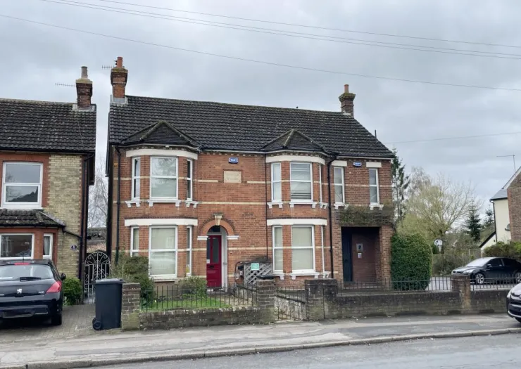 Red brick semi-detached house with bay windows and grey tiled roof.