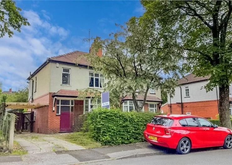 Semi-detached house with "For Sale" sign, red car parked outside, and front garden.