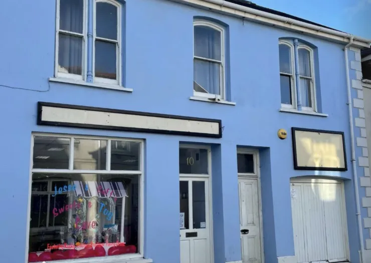 Light blue two-story commercial building with empty storefront signage.