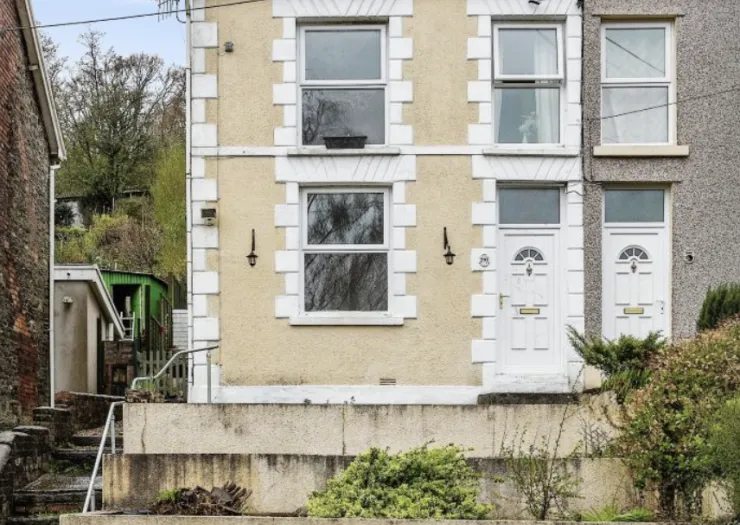 Cream terraced house exterior with white window frames and doors.