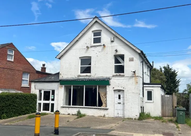 White two-story commercial building with empty storefront and green awning.