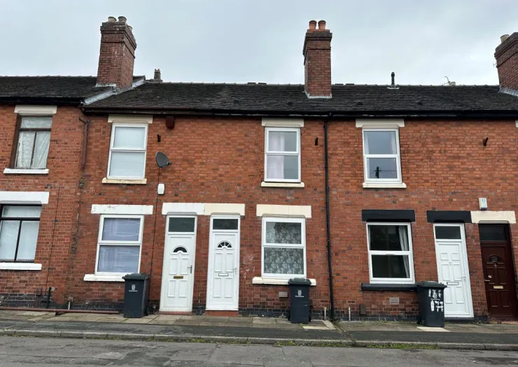 Red brick terraced house exterior with white and dark brown doors, chimneys, and bins on the street.