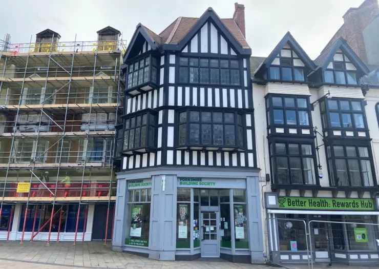 Yorkshire Building Society storefront with black and white timber framing, next to a building under scaffolding.