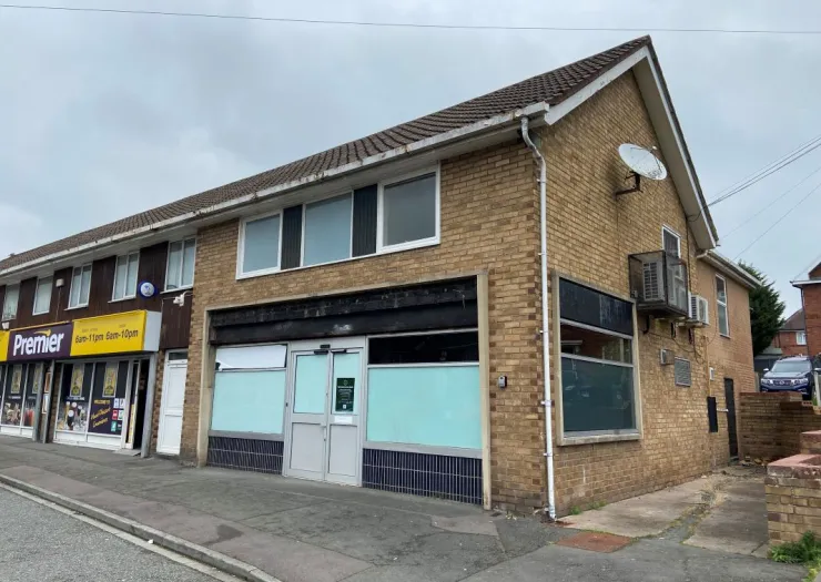 Brick commercial building with frosted windows and a "Premier" convenience store next door.