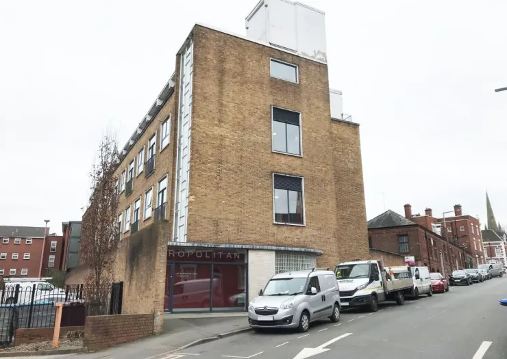 Metropolitan building exterior, tan brick, modern windows, street view.