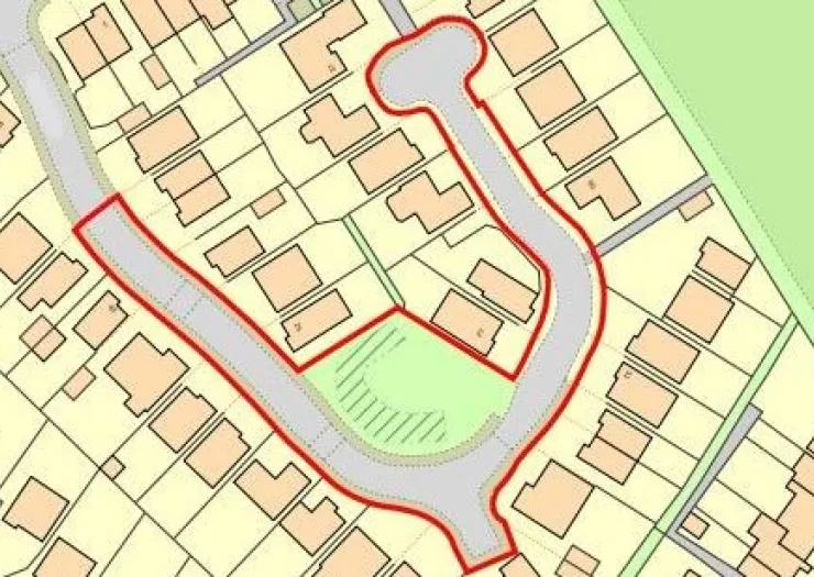 Property site map with highlighted red boundary around houses and green space.