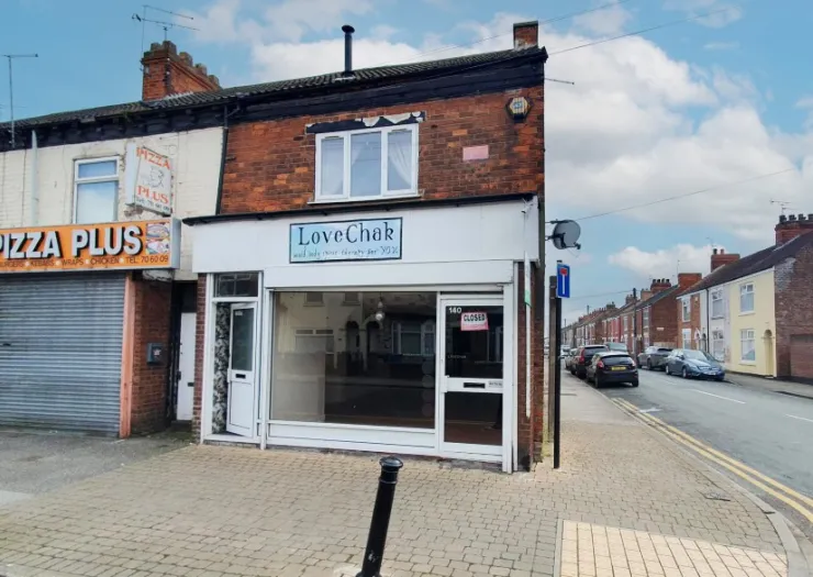 Empty "LoveChak" storefront with "Closed" sign, brick building, street view.