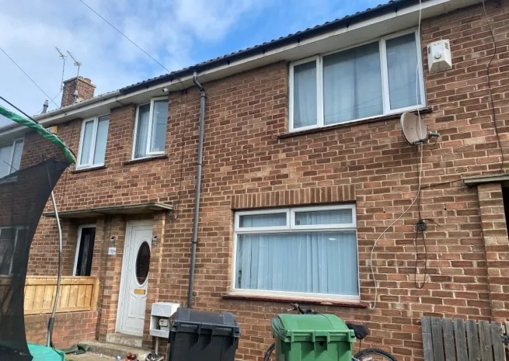 Red brick terraced house exterior with white windows and door.
