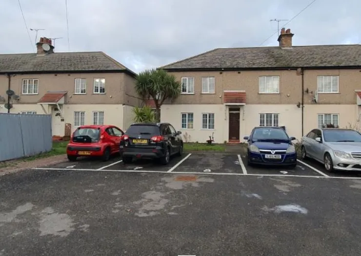 Residential building exterior with parking lot and cars.