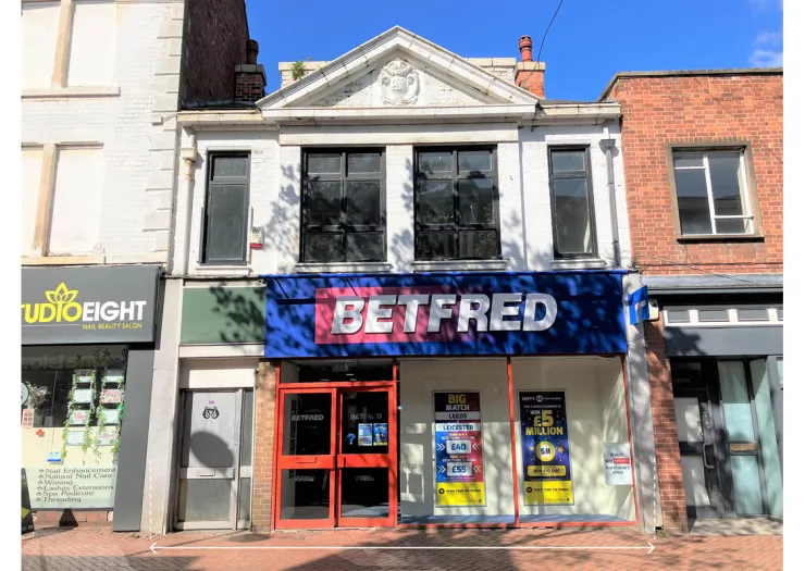 Betfred storefront with red doors, large signage, and promotional posters in a commercial building.