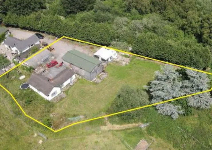 Aerial view of a rural property with house, outbuildings, and land outlined in yellow.