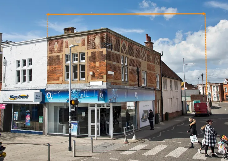 Commercial property with "O₂" storefront, brick facade, and pedestrians crossing street.