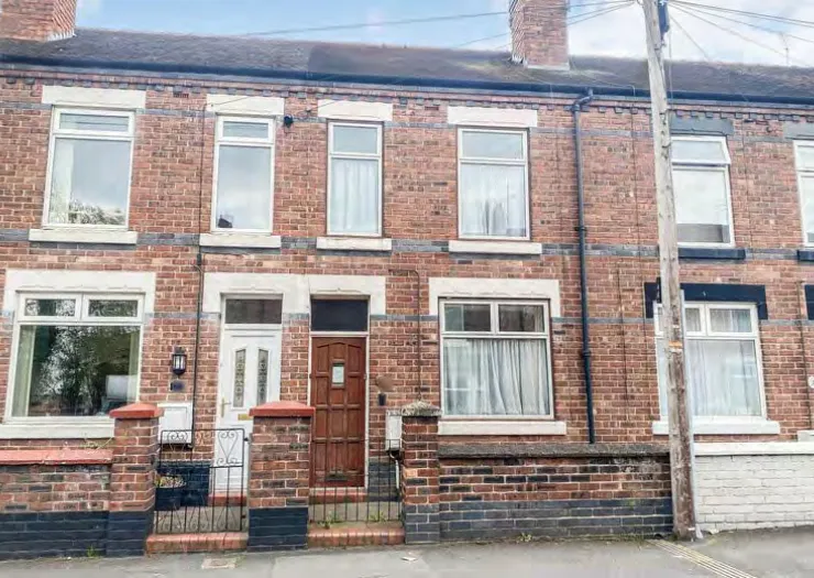Red brick terraced house exterior with white window frames and a brown wooden front door.