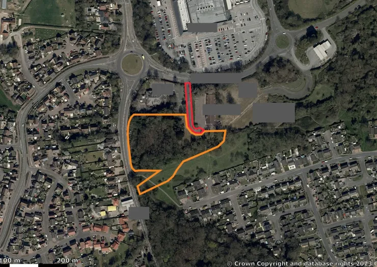 Aerial view of land outlined in orange, near a roundabout and residential area.