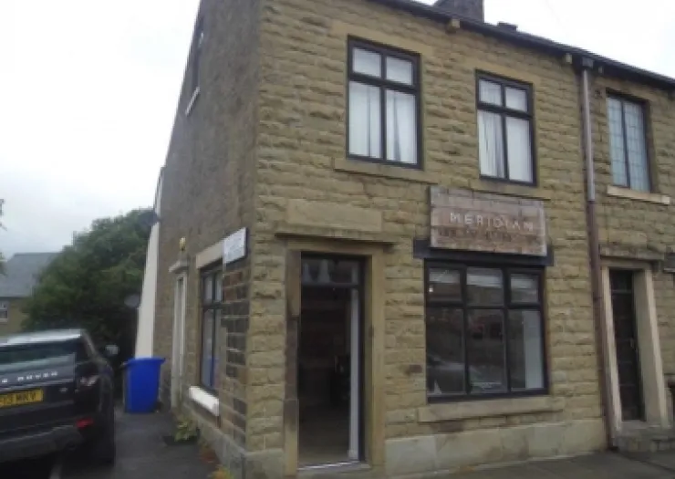 Stone commercial building with "Meridian" sign, black-framed windows, and open front door.