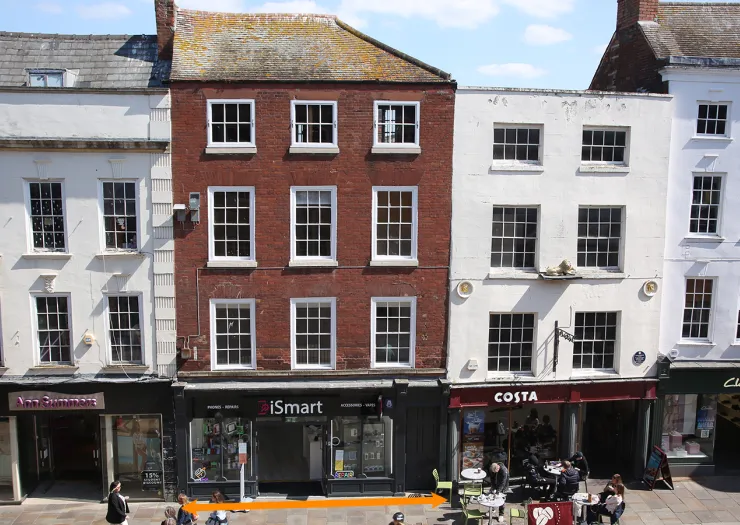 Red brick building between white buildings, with "iSmart" shop at street level. Costa Coffee next door.