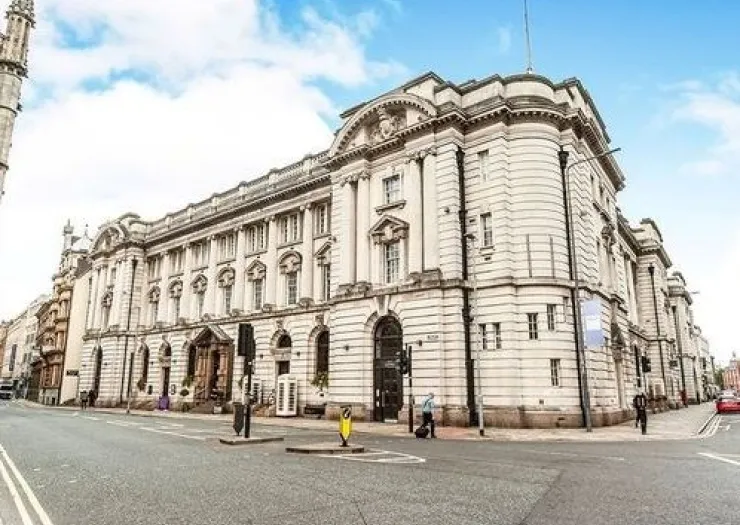 Grand white ornate building with columns on a city street corner.