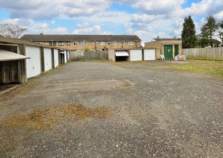 Row of garages with gravel driveway and fenced backyards.