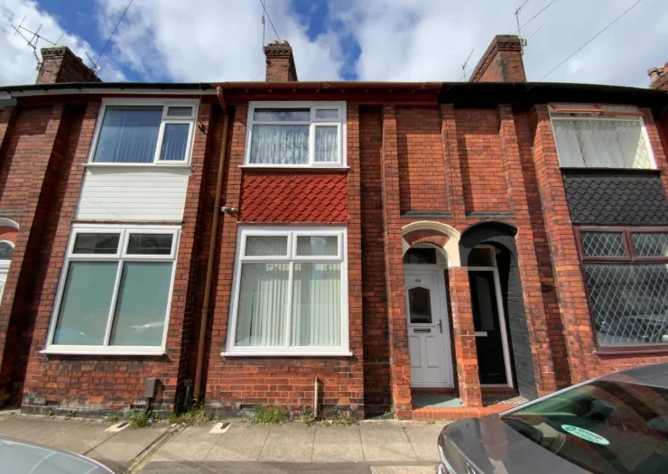 Red brick terraced house with white windows and decorative tilework.