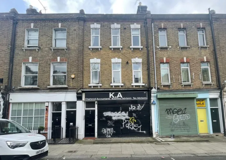 Brick row of London storefronts with apartments above. One storefront advertises "K.A. Chartered Accountants". Another has "S