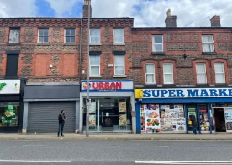 Brick storefronts with "Urban" eatery and supermarket on a city street.