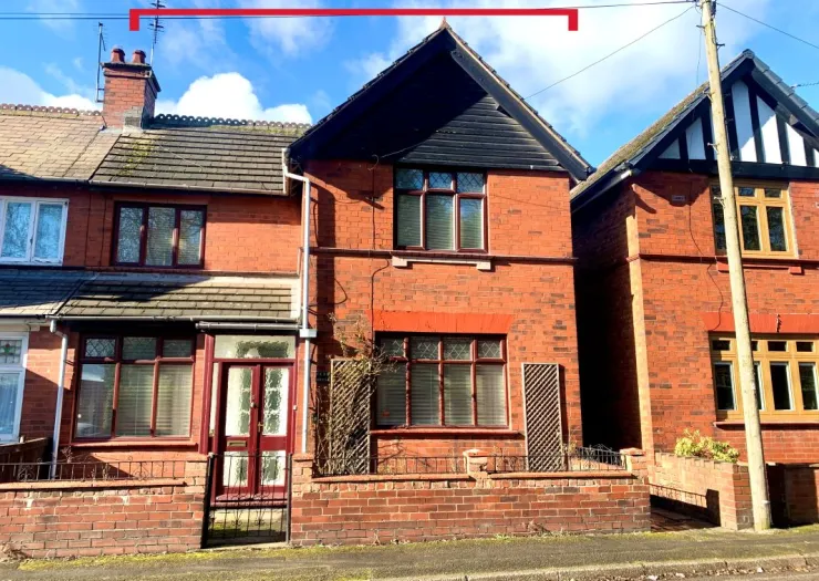 Red brick semi-detached house with dark wood gables and burgundy door and window frames.