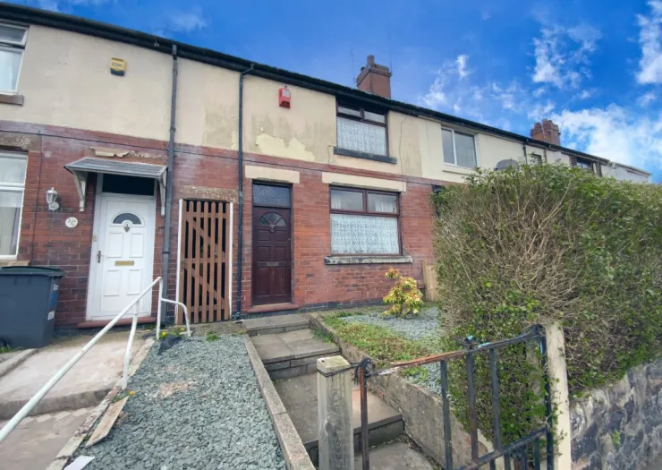 Brick terraced house exterior with white and brown doors, front garden, and gated steps.
