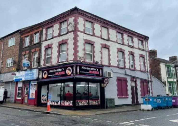 Headmaster's Barber" shop on a street corner, with red and white upper floors.