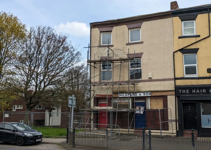 Hildyard & Son" building with scaffolding and boarded-up storefront undergoing renovations.