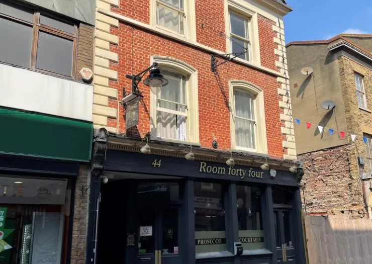 Room forty four" bar exterior with dark facade and red brick upper floors.