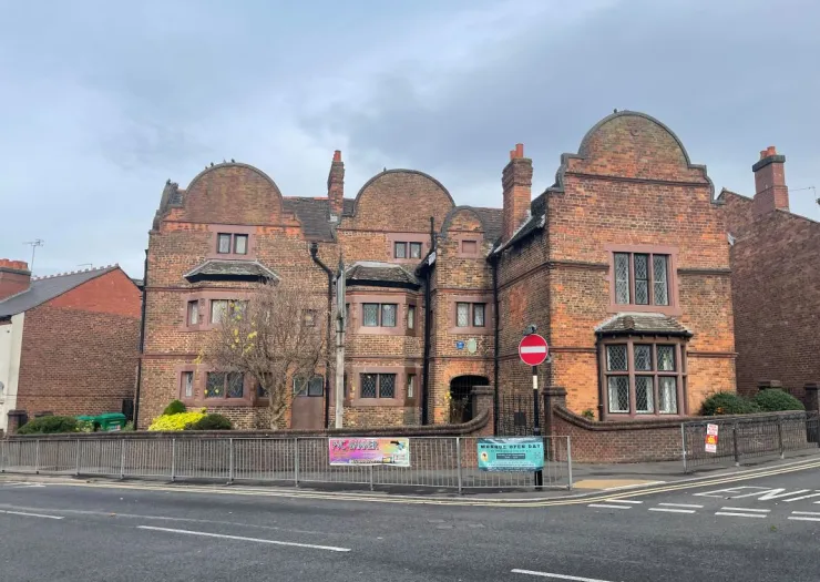 Brick building with curved gables, fenced yard, and "Mersey Open Day" banner.