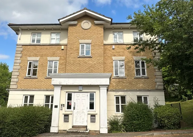 Modern tan brick apartment building with white entryway and columns.