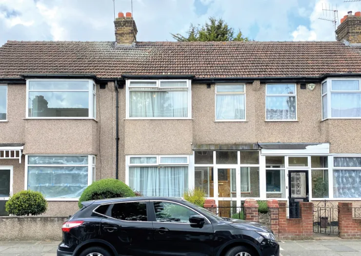 Semi-detached house with tiled roof, bay windows, and small front garden. A black car parked on the street.