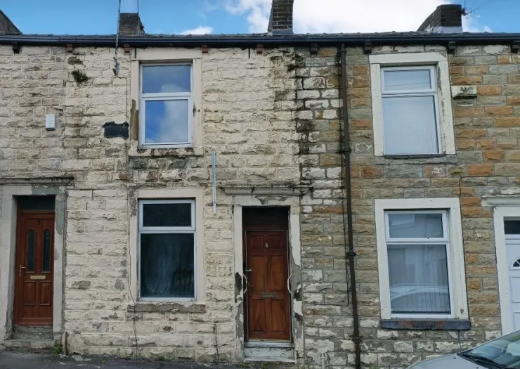 Stone terraced house exterior with some peeling paint, needing renovation.
