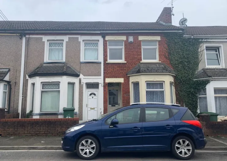 Terraced house exterior with bay window and parked blue car.