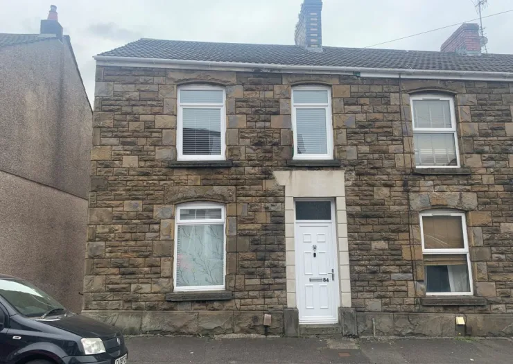 Stone terraced house with white windows and door.