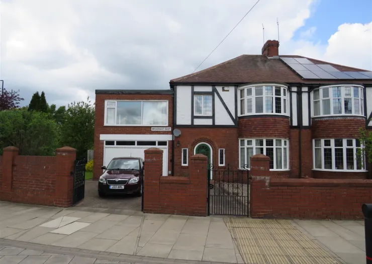 Red brick house with bay windows, attached garage, and solar panels.