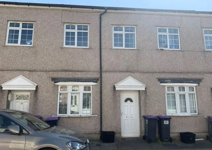 Exterior of a semi-detached house with white front door and windows, pebble-dash walls, and wheelie bins.