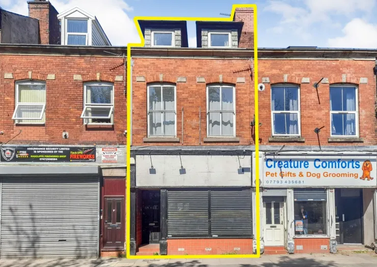 Red brick commercial property with two-story dormer windows and ground-floor storefront.
