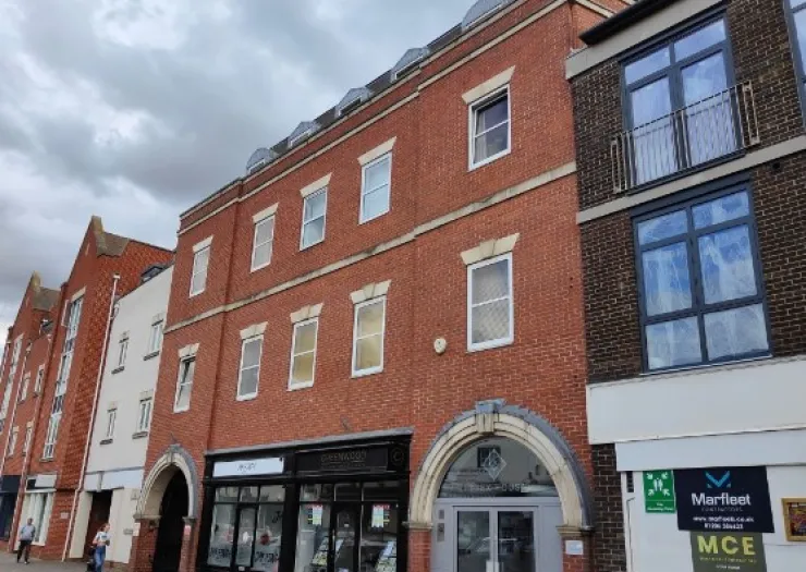 Modern red brick mixed-use building with retail shops on ground floor and arched entryways.