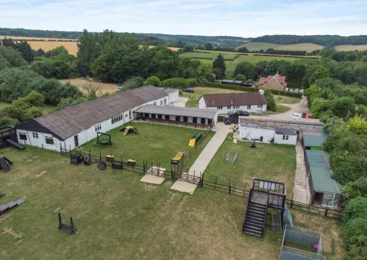 Aerial view of dog kennels, training area, and outbuildings in a rural setting.
