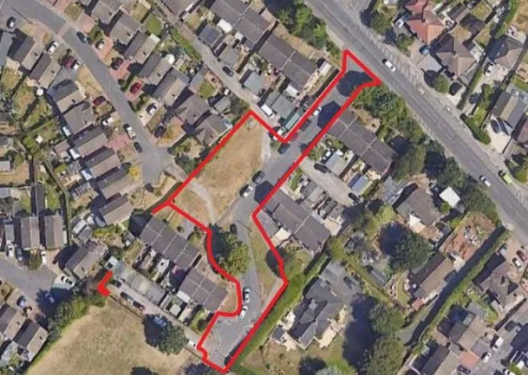 Aerial view of land outlined in red, amidst residential houses and roads.